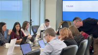Room full of people working on laptops at a desk, reciving training