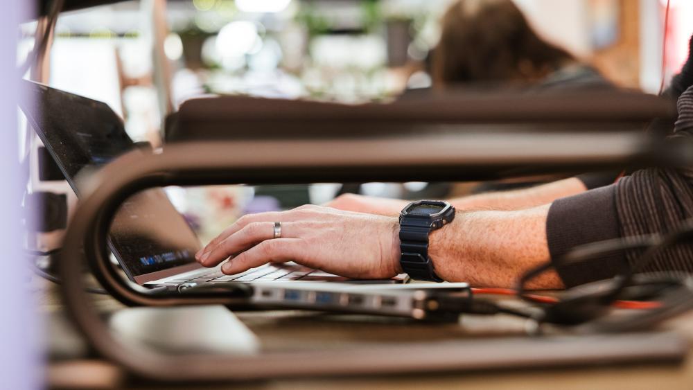 person wearing a digital watch typing on a laptop