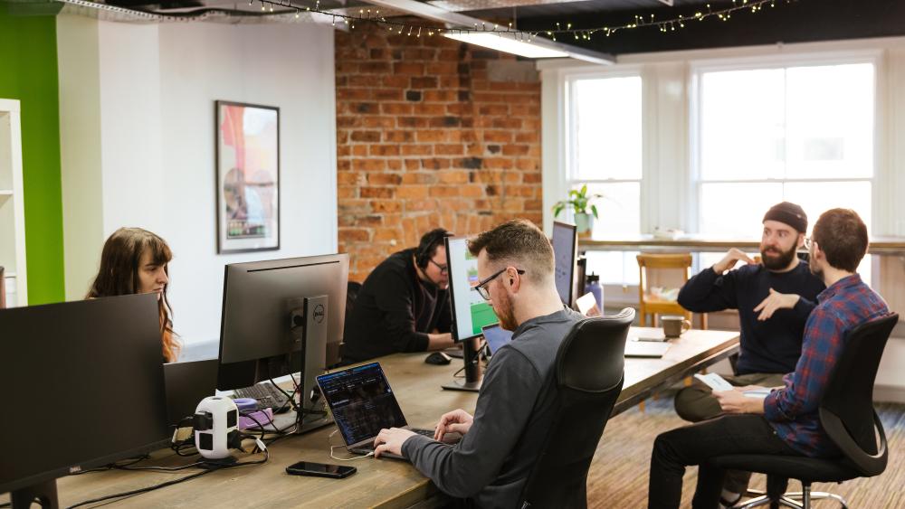 five people sat at desks working