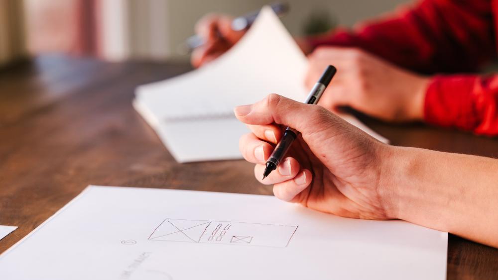 Holding a pen above a notepad