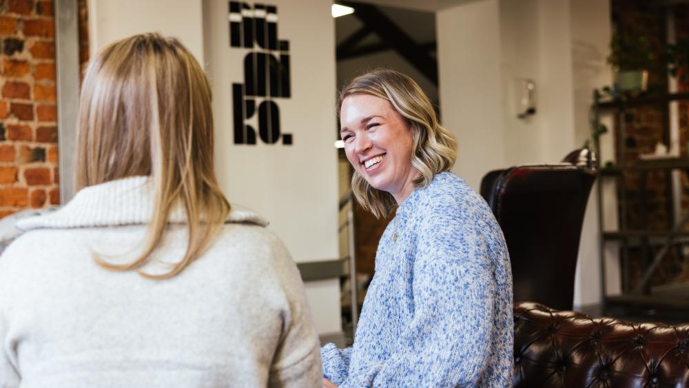 two people sat talking to eachother, one is smiling warmly