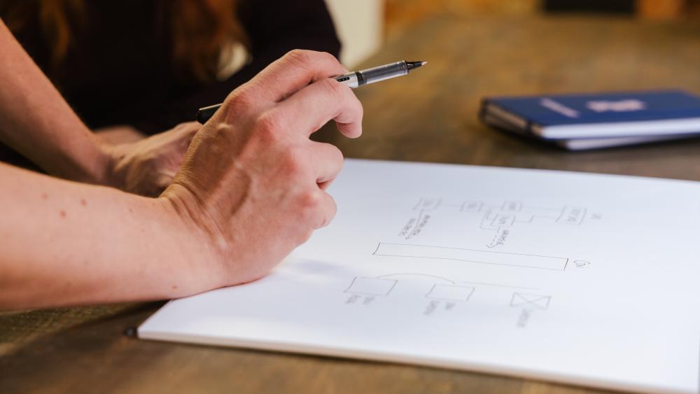 Hand holding a pen above a process diagram