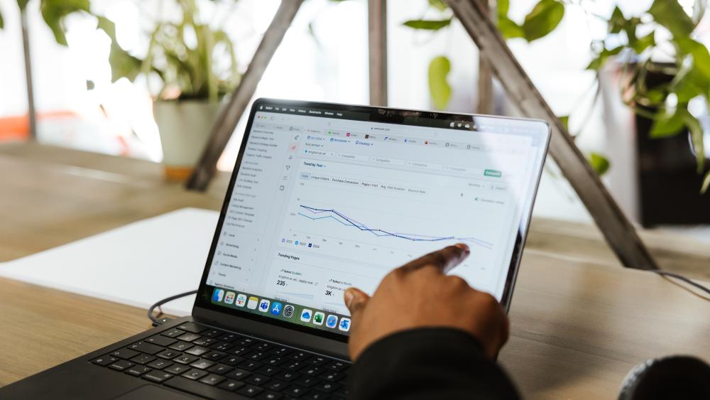 Person pointing at a analytics chart on a laptop
