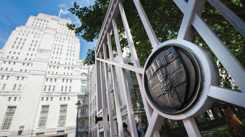 The Senate House building of the University of London, with a gate with the University of London's crest in the foreground.