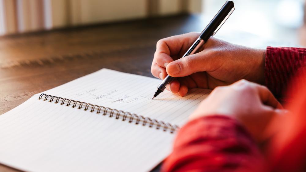 A close up of someone writing in a notebook
