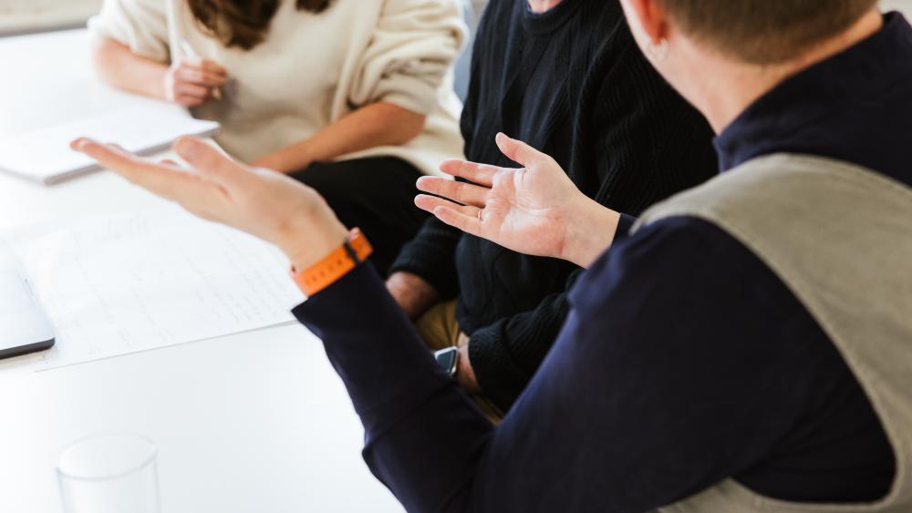 Person speaking in meeting to two others
