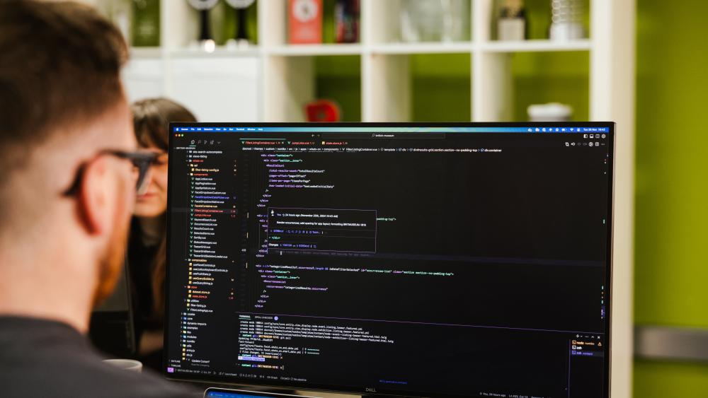 A developer looking at a desktop monitor with coding on the screen