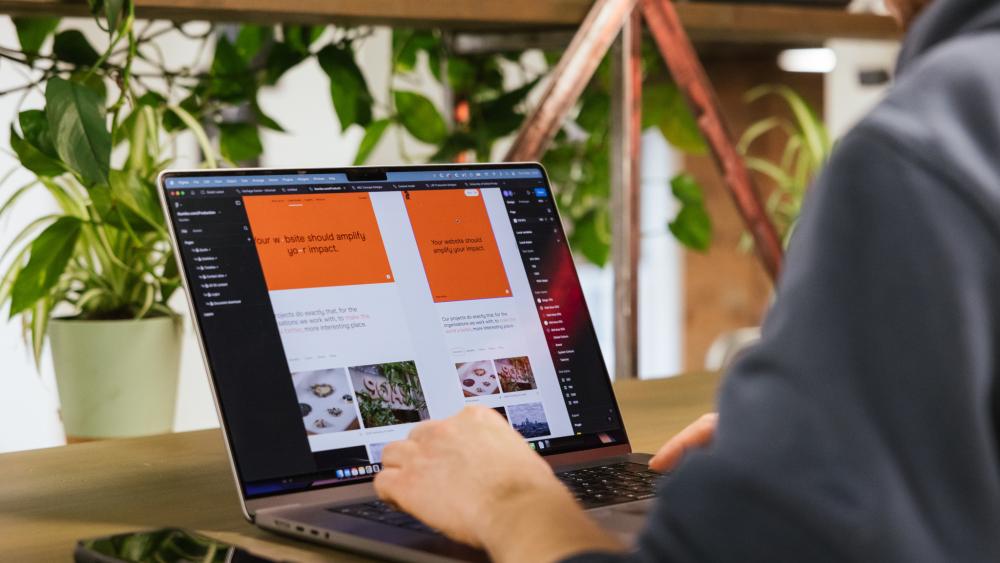 A Numiko designer working on a laptop that is showing website designs