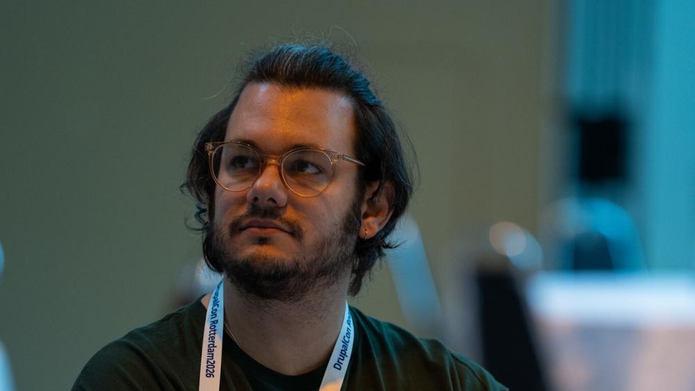 Jacob looking up at a screen while working at their laptop at a conference