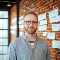 Paul posing for a headshot in front of a brick wall